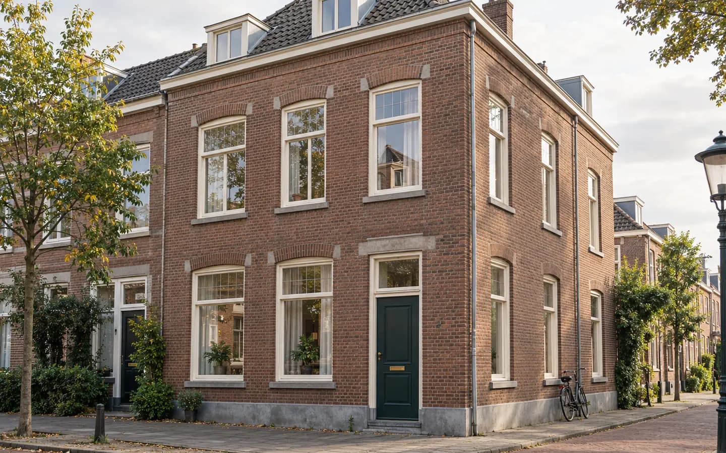Bakstenen hoekpand met een groene voordeur en een fiets tegen de gevel